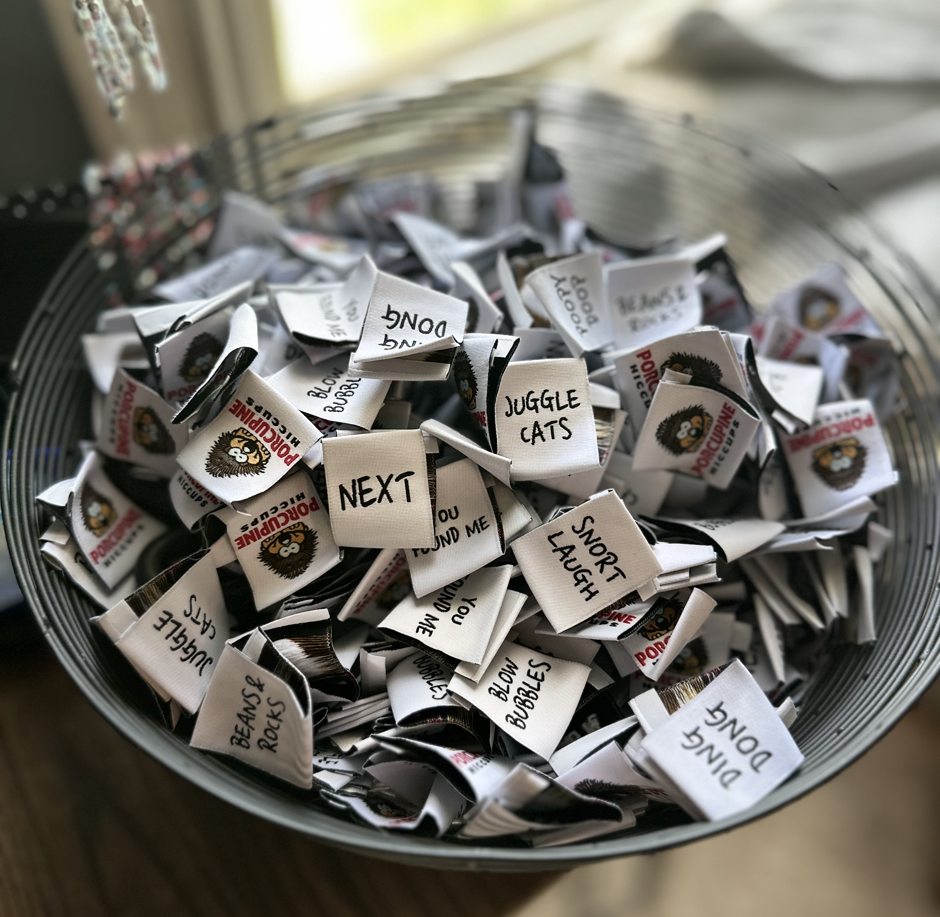 Folded t-shirts with cartoon designs. Animated flower, pizza cloud rainbow, and smiling alien logos laid in a stack on a t...