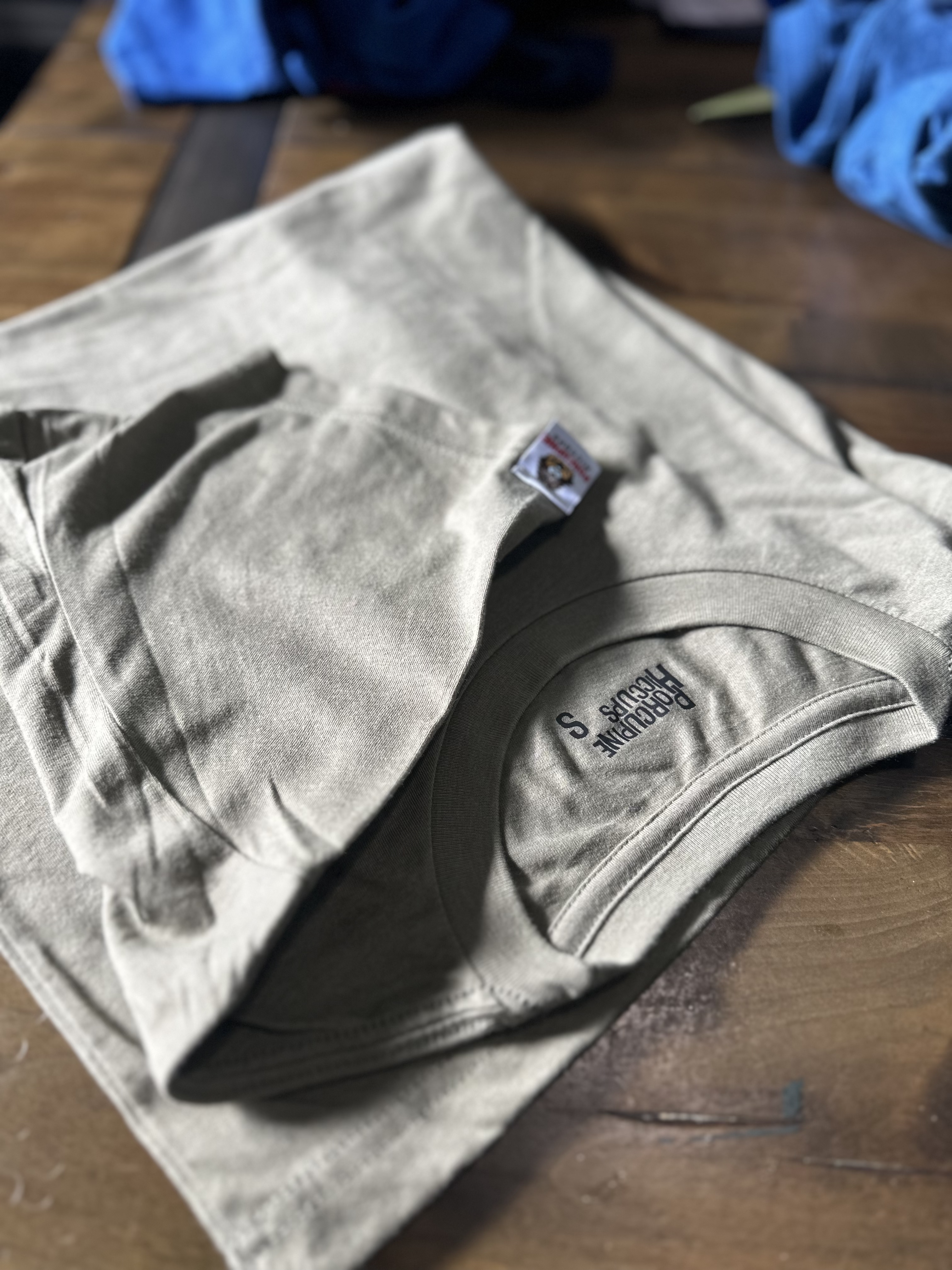 A stack of four cartoon-print kids' T-shirts arranged into a pile and placed on a wooden table adorned with small colorful...