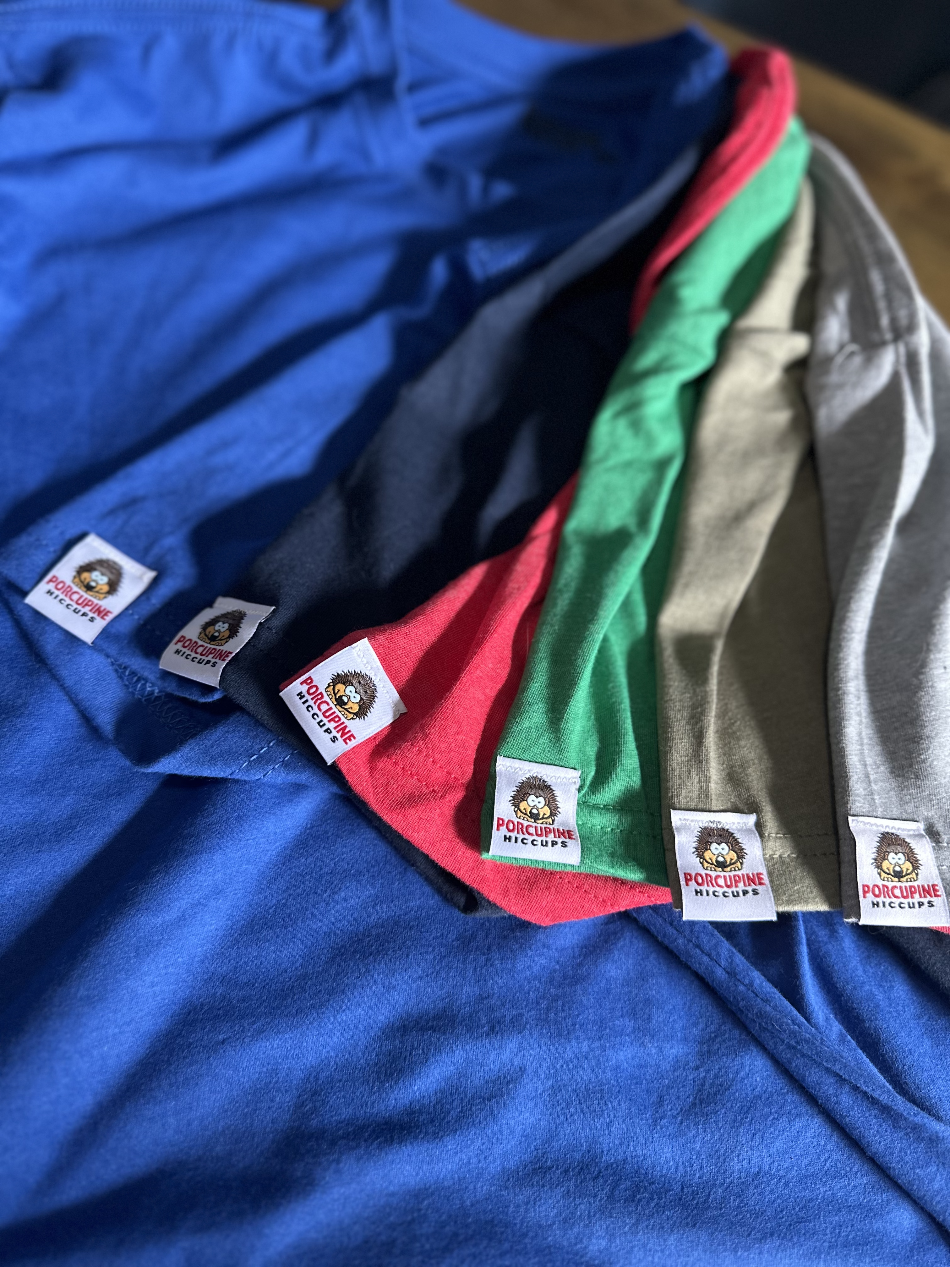 An illustrator's desk with a happy coffee mug, colorful pastels and paintbrushes, a notebook, and many small pieces of art.